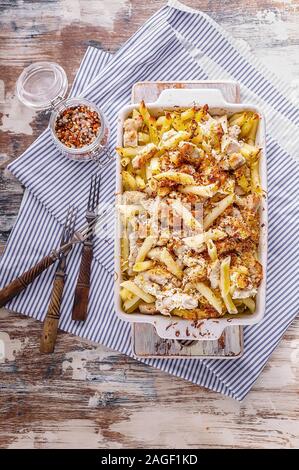 Baked penne pasta with turkey meat, smoked cheese and spices. Traditional Italian dish in ceramic baking dish. Vertical shot Stock Photo