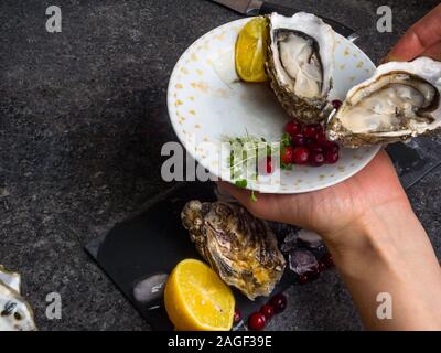 Open oyster in hands, against a background of open oysters, selective focus Stock Photo