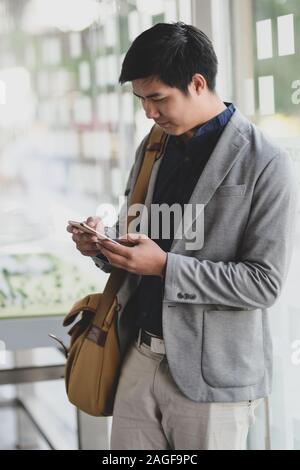 Portrait of young businessman hiding smartphone while leaving the office room Stock Photo