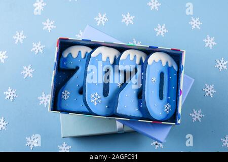 Gift present box with holiday cookies. Christmas of New Year 2020 Concept. Ginger biscuits cookies of the form of numbers 2020 on blue background. Top Stock Photo