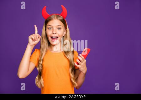 Photo of small lady horns headband holding telephone raise finger have idea for new social network post demon theme wear orange t-shirt isolated Stock Photo