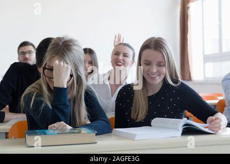 University students listening while Male professor explain lesson to them and interact with them in the classroom.Helping a students during class. Uni Stock Photo