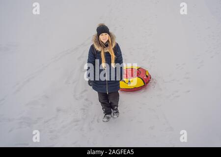 winter, leisure, sport, friendship and people concept - woman sliding down on snow tubes Stock Photo