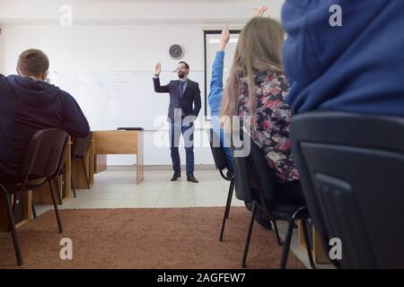 Male professor explain lesson to students and interact with them in the classroom.Helping a students during class. Stock Photo