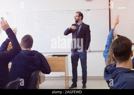 Male professor explain lesson to students and interact with them in the classroom.Helping a students during class. Stock Photo