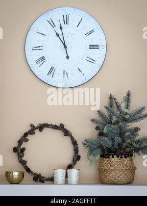 Decorating living room with natural materials - wreath made from larch branches and some fir tree branches put in a basket. Watch hanging on a wall Stock Photo