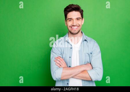 Photo of amazing business guy in excited mood with crossed hands looking forward to start working day wear casual denim shirt isolated over green Stock Photo