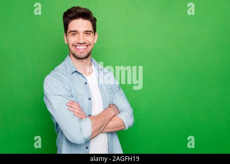 Photo of amazing business guy in excited mood with crossed hands looking forward to start working day wear casual denim shirt isolated over green Stock Photo