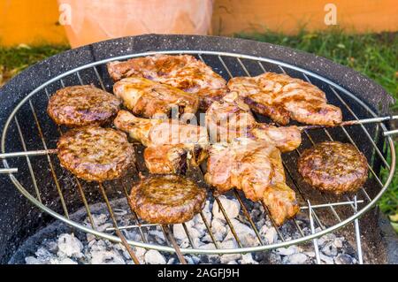 meat being cooked on BBQ in garden in summer Stock Photo