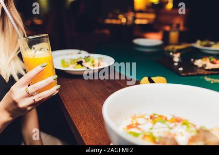 Restaurant or cafe table with plate of salads and wine. Two people talking on background. Toned picture Stock Photo