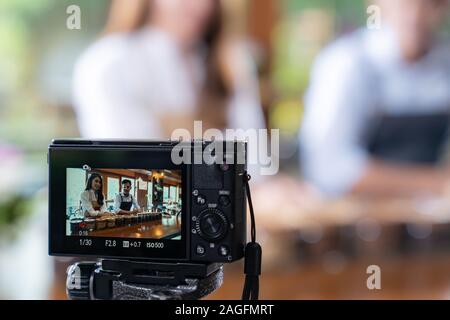 VLOG of  young adult asian owner entrepreneur review cafe coffee shop and live in social media for online marketing with camera in cafe. Using for sta Stock Photo