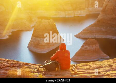 Unusual natural background. Reflection Canyon on Lake Powell, Utah, USA. Inspiring hiking scene-man resting on the beautiful sunset point. Stock Photo