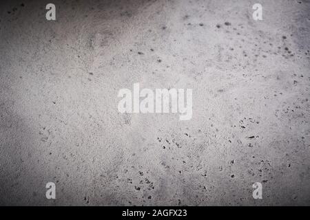 Full frame textured pitted grey cookware background with vignette for food placement or use as a design template