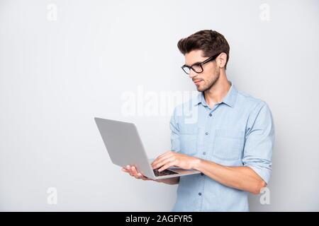 Photo of thoughtful focused clever interested freelancer holding laptop with hands wearing eyeglasses working on deadline project isolated grey color Stock Photo