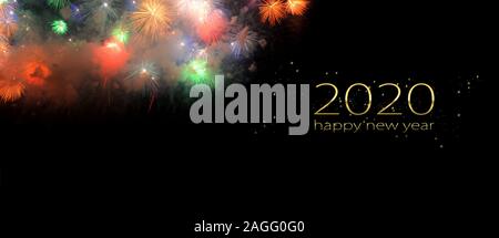 Colorful fireworks that explode and fill the darkness of the night sky on a black background with the words 2020 happy new year. Stock Photo