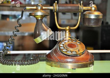 A corroded brown retro dial phone on a warm golden colored wooden deck. Stock Photo