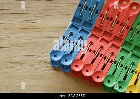 colorful plastic clothes peg clipping hard white paper on wooden board Stock Photo