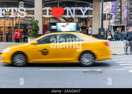 I Love New York gift shop sign and blurred yellow taxi cab passing, Times Square, Manhattan, New York, USA Stock Photo