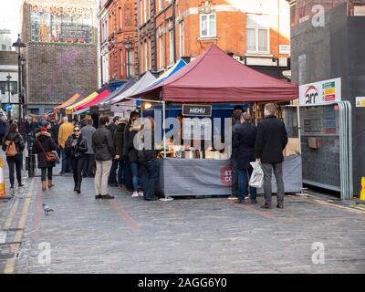 A street food market in Soho London UK with stalls selling food and customers in the street Stock Photo