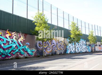 Colourful murals & graffiti on Peace wall,or Peace Line, running along Cupar Way in Belfast. It is one of the many separation barriers in N. Ireland Stock Photo