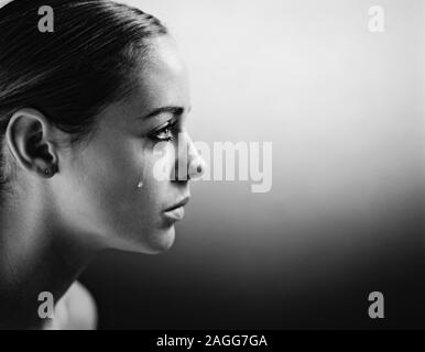 Close up of young woman's face profile with teardrop. Stock Photo