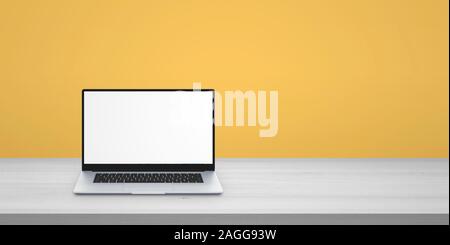 Laptop on desk with copy space beside. Isolated screen for mockup. Yellow wall in background Stock Photo