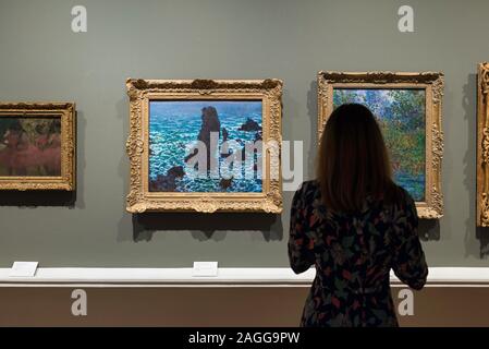 Woman gallery, rear view of a woman looking at  Les Pyramides At Port-Coton (1886) by Claude Monet, Ny Carlsberg Glyptotek museum, Copenhagen Denmark