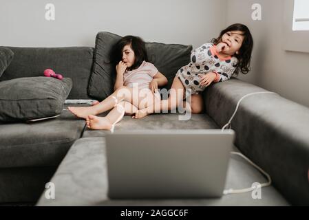 Sisters relaxing in front of laptop on couch Stock Photo