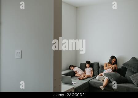 Mother and daughters relaxing on couch in living room Stock Photo
