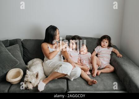 Mother and daughters relaxing on couch in living room Stock Photo