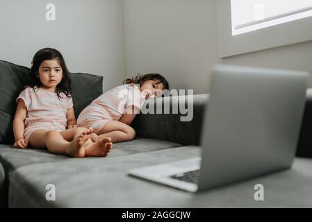 Sisters relaxing in front of laptop on couch Stock Photo