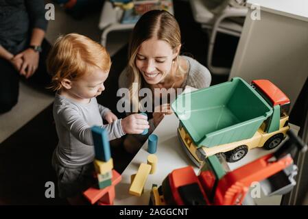 Mother and son playing with toy blocks in living room Stock Photo