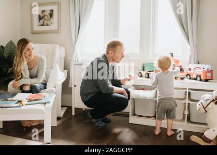 Couple watching son play with toy trucks in living room Stock Photo