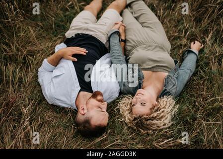 Young couple holding hands and talking on brown grass Stock Photo