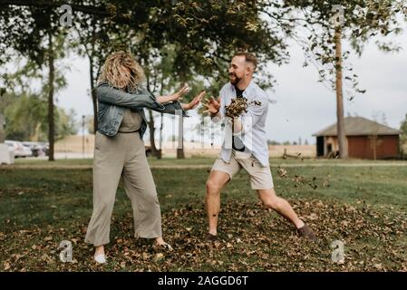 Young man throwing leaves playfully at woman in countryside Stock Photo