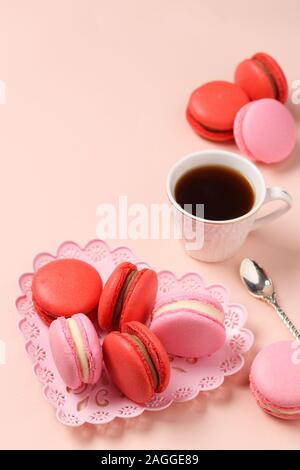 Delicious sweet macaroons in a figural plate on a pink background, red and pink macaroons, Concept for Valentine's Day, March 8 and Mother's Day Stock Photo