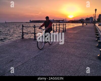 Thessaloniki, Macedonia / Greece - May 05, 2008: Motion blurred bicycle rider, at waterfront sidewalk in Thessaloniki, during sunset time. Stock Photo