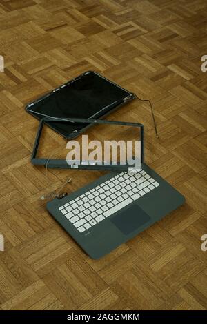 A broken computer on a wood block floor. Stock Photo