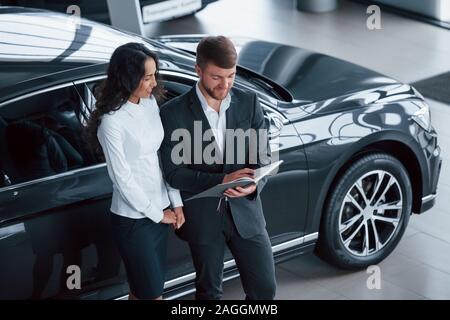 Making some notes. Female customer and modern stylish bearded businessman in the automobile saloon Stock Photo