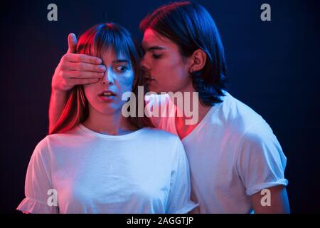 This will shock you. Couple standing in dark room with red and blue neon lighting Stock Photo