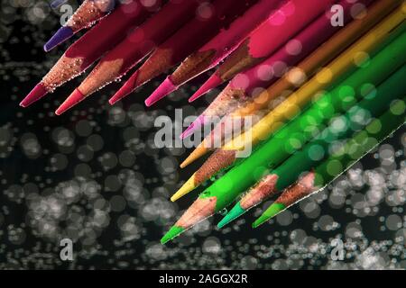 Colored pencils in water with drops on a bokeh background. Background blurred multicolored pencils Stock Photo