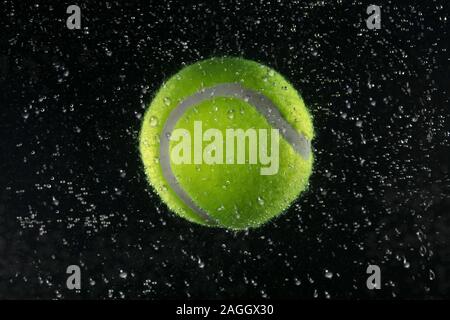 Tennis ball in the water on a dark background Stock Photo