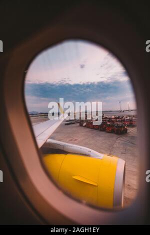 The view from the window of the airplane porthole at dawn at the airport of Barcelona. Theme of romance on a journey. Tourism and air travel. View Stock Photo
