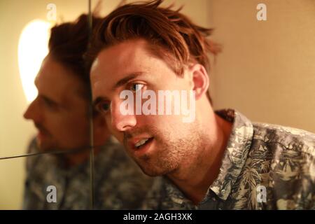 Shallow focus shot of a male whit his head leaned against a mirror Stock Photo