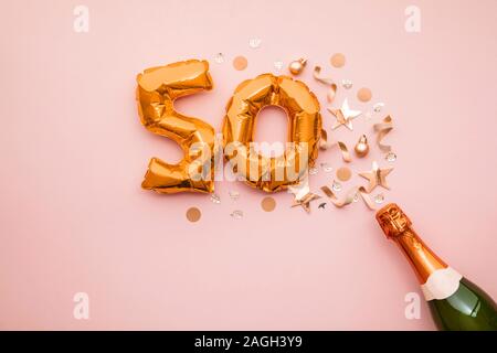 Happy 50th anniversary party. Champagne bottle with gold number balloon. Stock Photo