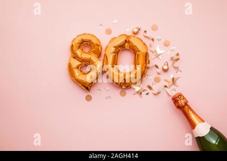 Happy 80th anniversary party. Champagne bottle with gold number balloon. Stock Photo
