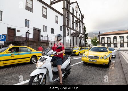 Man on scooter and yellow taxis on the street, Funchal, Madeira, Portugal Stock Photo