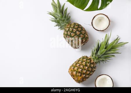 Pineapples, coconuts and palm leaves on white background, space for text Stock Photo