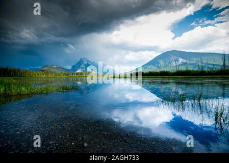 Cloudy sky and the mountains reflected in the water of the lake Stock Photo