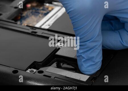 Technician connecting hard drive HDD cable to a laptop computer.  Computer updrade concept Stock Photo